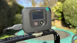 A closeup of the optional receiver unit attached to a cold shoe mount on a smartphone’s cage
