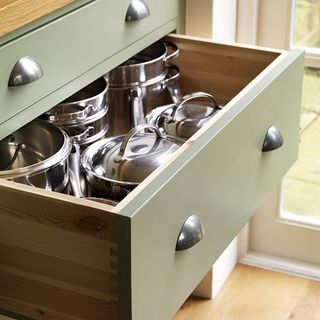 cream kitchen with soft green painted cupboards, wooden floors and countertops