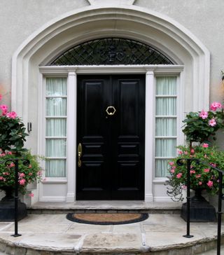 Glossy black front door surrounded by foliage