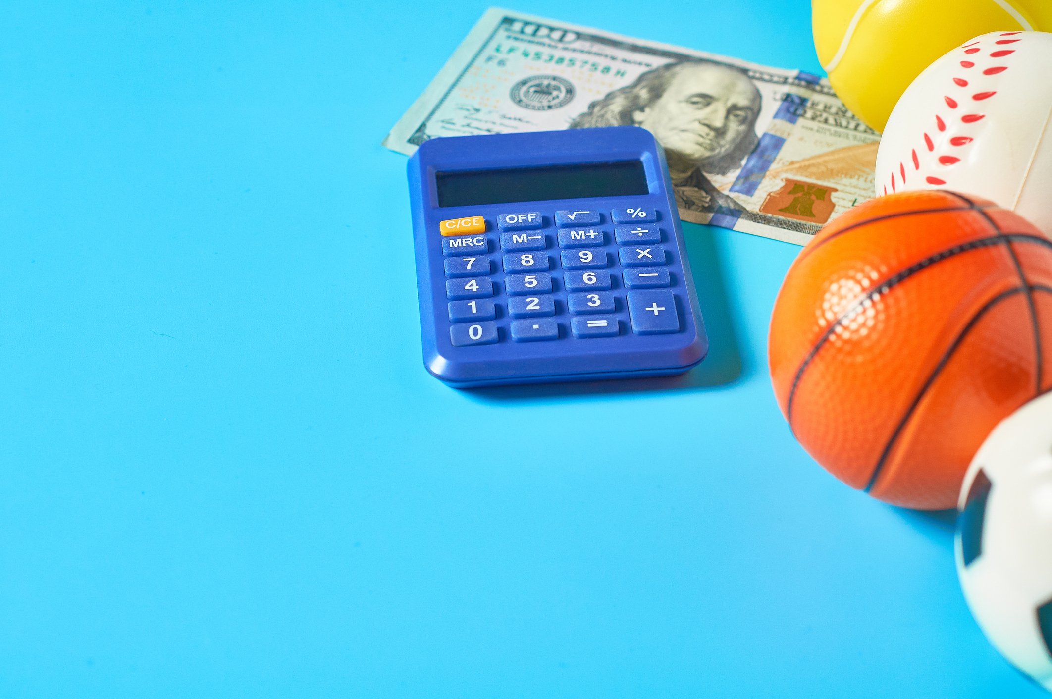 various sports balls with a calculator and a one hundred dollar bill