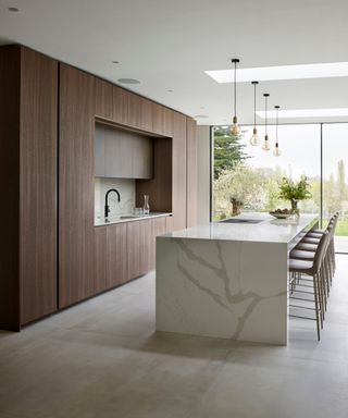 A modern kitchen with quartz kitchen island and tall wooden kitchen storage