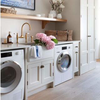 kitchen with white sink, light grey cabinets, white washing machine, pink flowers and wooden flooring