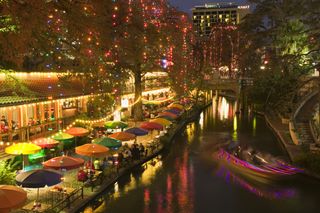 Colorful view of restaurant umbrellas and riverwalk canal in San Antonio, Texas at night