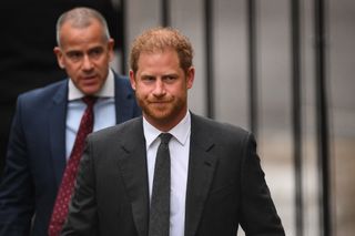 a medium shot of Prince Harry leaving court followed by his lawyer