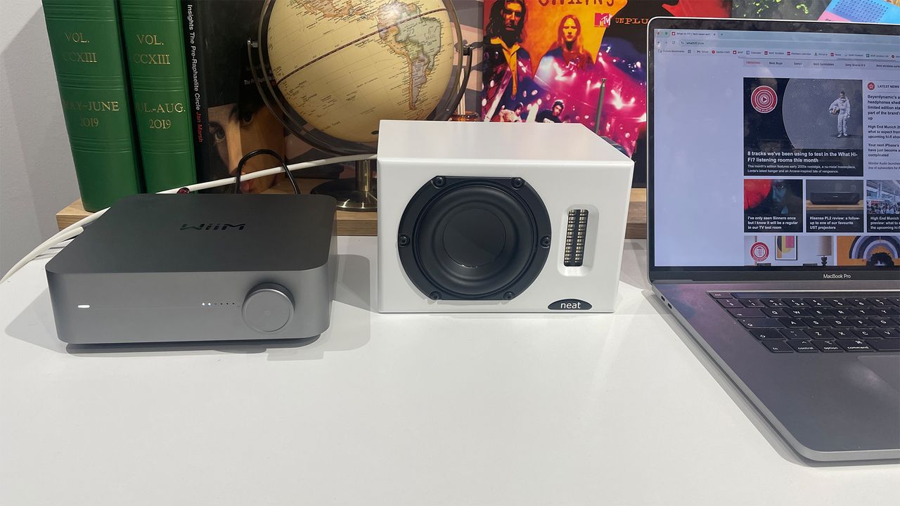 Neat Iota II speakers and WiiM Amp Pro placed on a table next to laptop