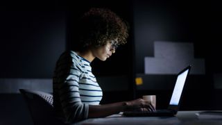 Woman working on laptop in dark