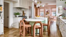 Cheerful eat-in kitchen area featuring a mint green island surrounded by contemporary peach dining chairs