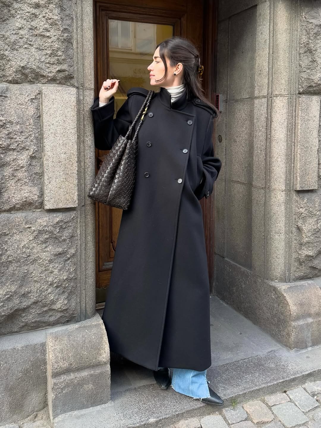 Woman in an elegant long black coat.