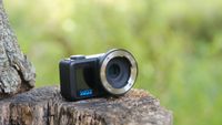 The GoPro Mission 1 ILS mirrorless camera photographed outdoors on a tree stump