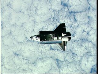 This full view of Challenger in space was taken by a satellite. A heavily cloud-covered portion of the Earth forms the backdrop for this scene of Challenger in orbit. This image was taken during Challenger's STS-7 mission, which launched on June 18, 1983.
