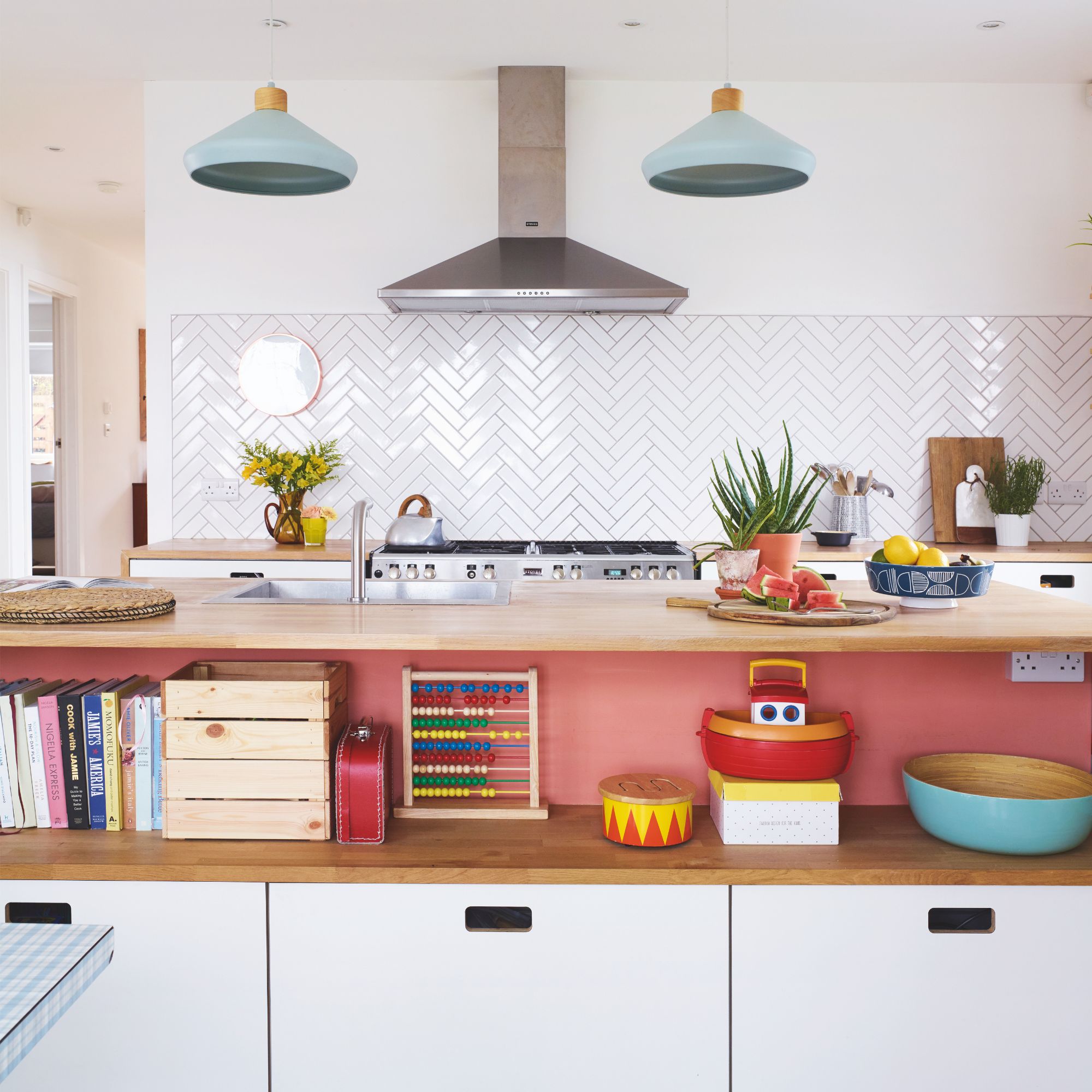 Kitchen with white tiles and a wooden kitchen island with white cabinets and pink accents