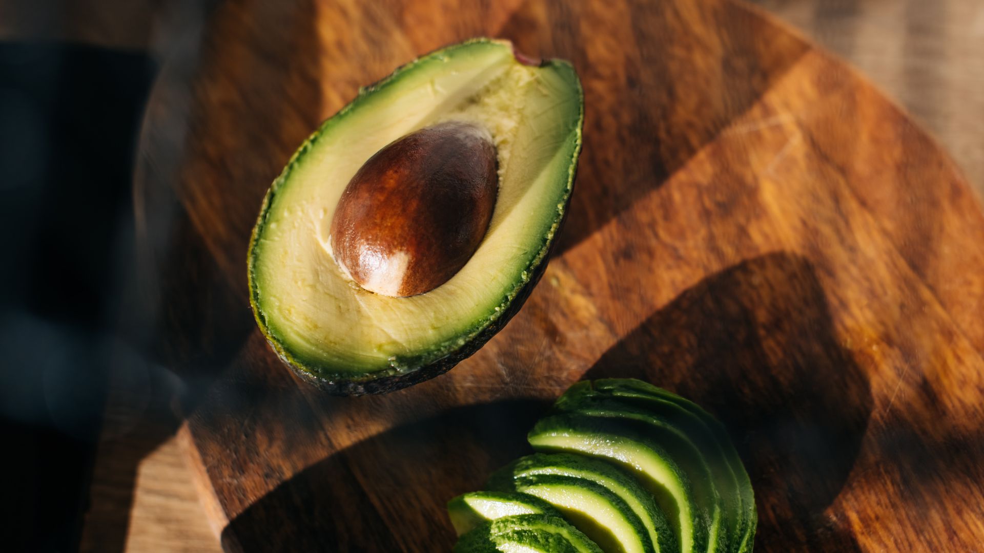 Half an avocado on wooden chopping board