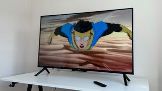The 50-inch Amazon Fire TV Omni QLED on a white table with an image from animated TV show Invincible on the screen