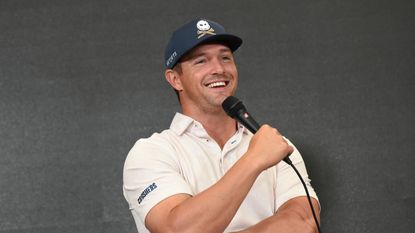 Bryson DeChambeau smiles with a microphone in his hand at a LIV Golf press conference