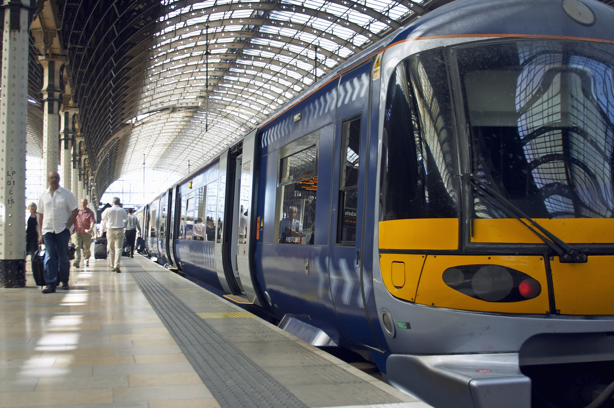 A train waiting at a busy station with passengers walking by