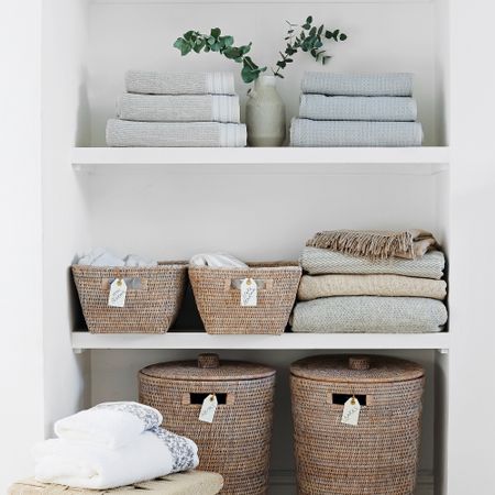 Linen cupboard with folded towels and labelled storage baskets