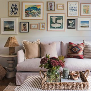 A living room with a light pink sofa and a gallery wall display hung above it