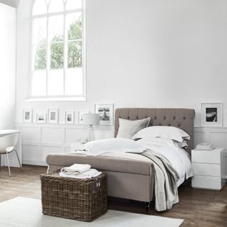 A white light filled room with bed and wicker storage basket