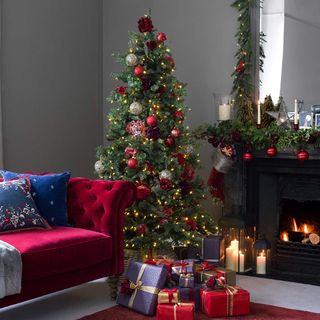 Christmas tree with red rose decorations by red sofa