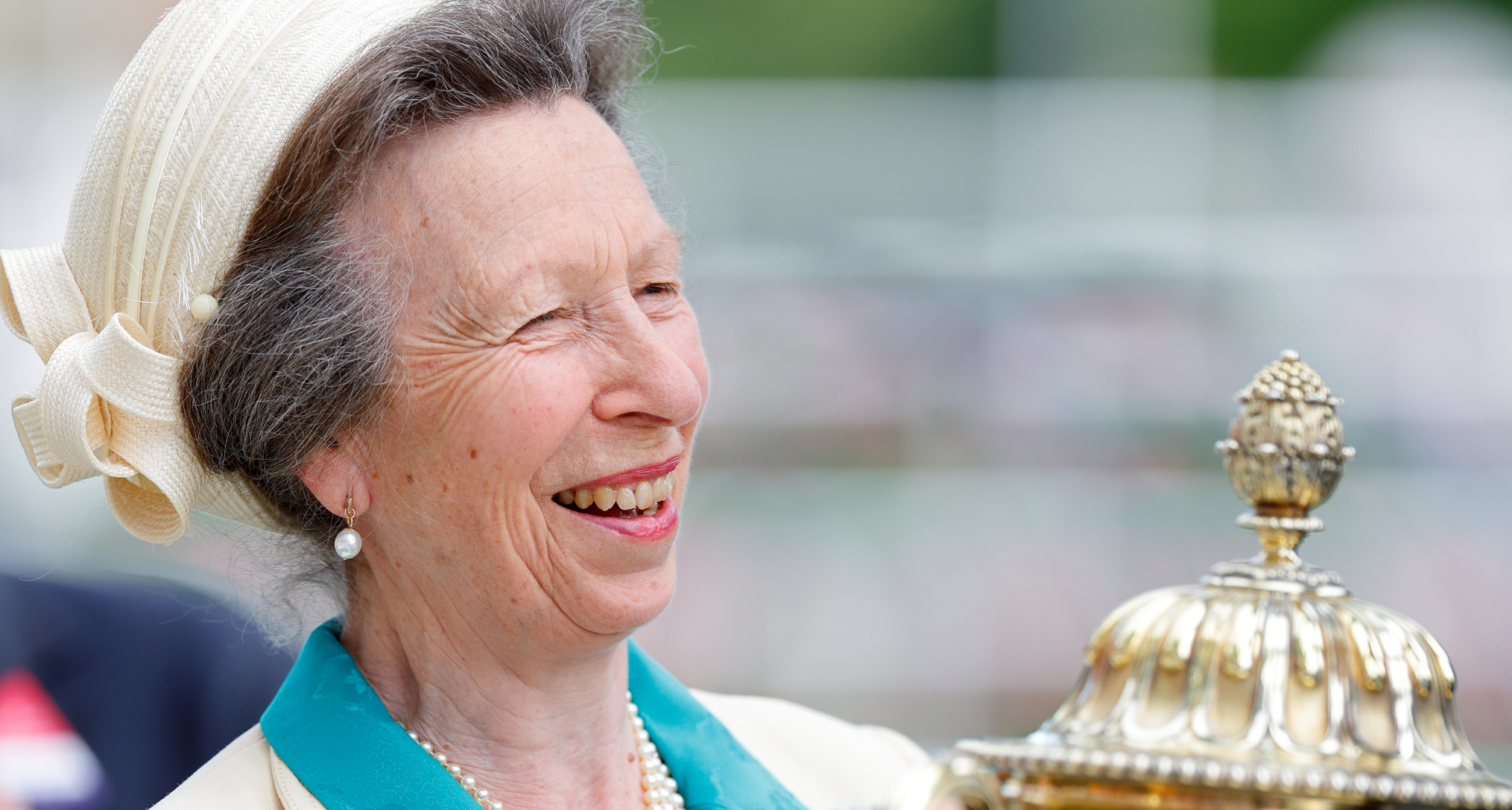 Princess Anne laughing and holding a gold trophy