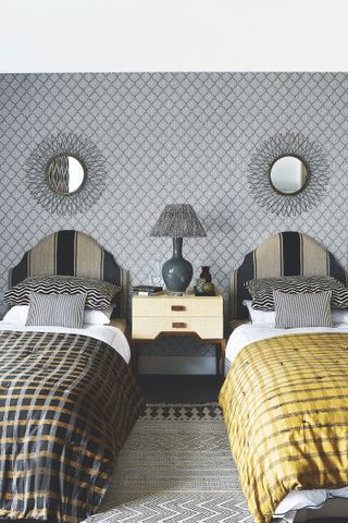twin beds in a grey room with ochre and monochrome bedding