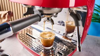 a red smeg espresso machine with burr grinder is photographed against a blue background