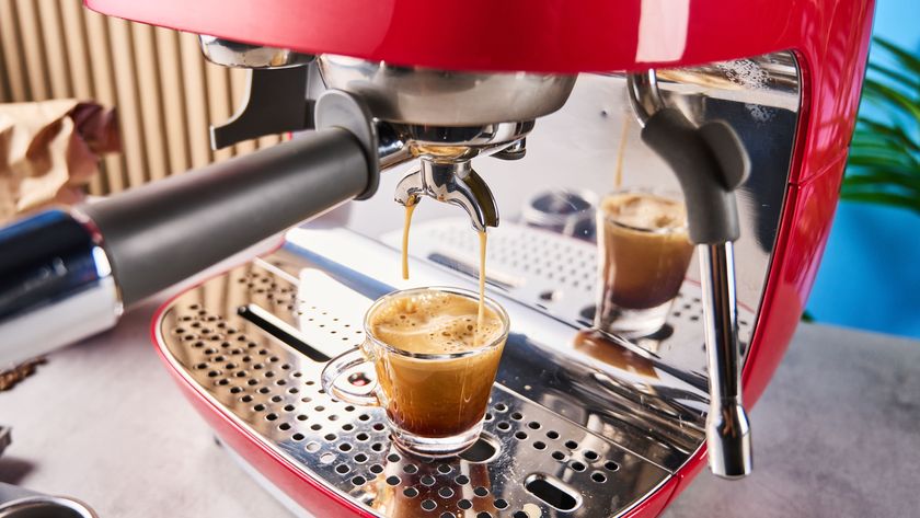 a red smeg espresso machine with burr grinder is photographed against a blue background