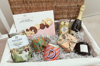 A large hamper filled with Prosecco, biscuits, coffee, candle, bath bombes, Ferrero Rochers, and two personalised mugs