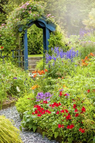an arbor at the end of a path with colorful flowers