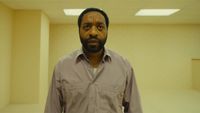 Chiwetel Ejiofer wears a button down shirt and wanders around a seemingly abandoned office in Backrooms. 