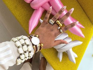 a hand is pictured with many rings and some bracelets and bangles on