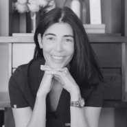 a black and white photo of a woman with dark hair smiling at the camera
