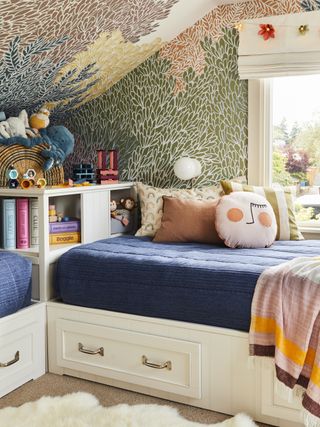 A kids room with a blue day bed covered with cushions and soft toys