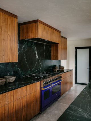 kitchen with dark wood cabinets range cooker black backsplash and pale floor tiles