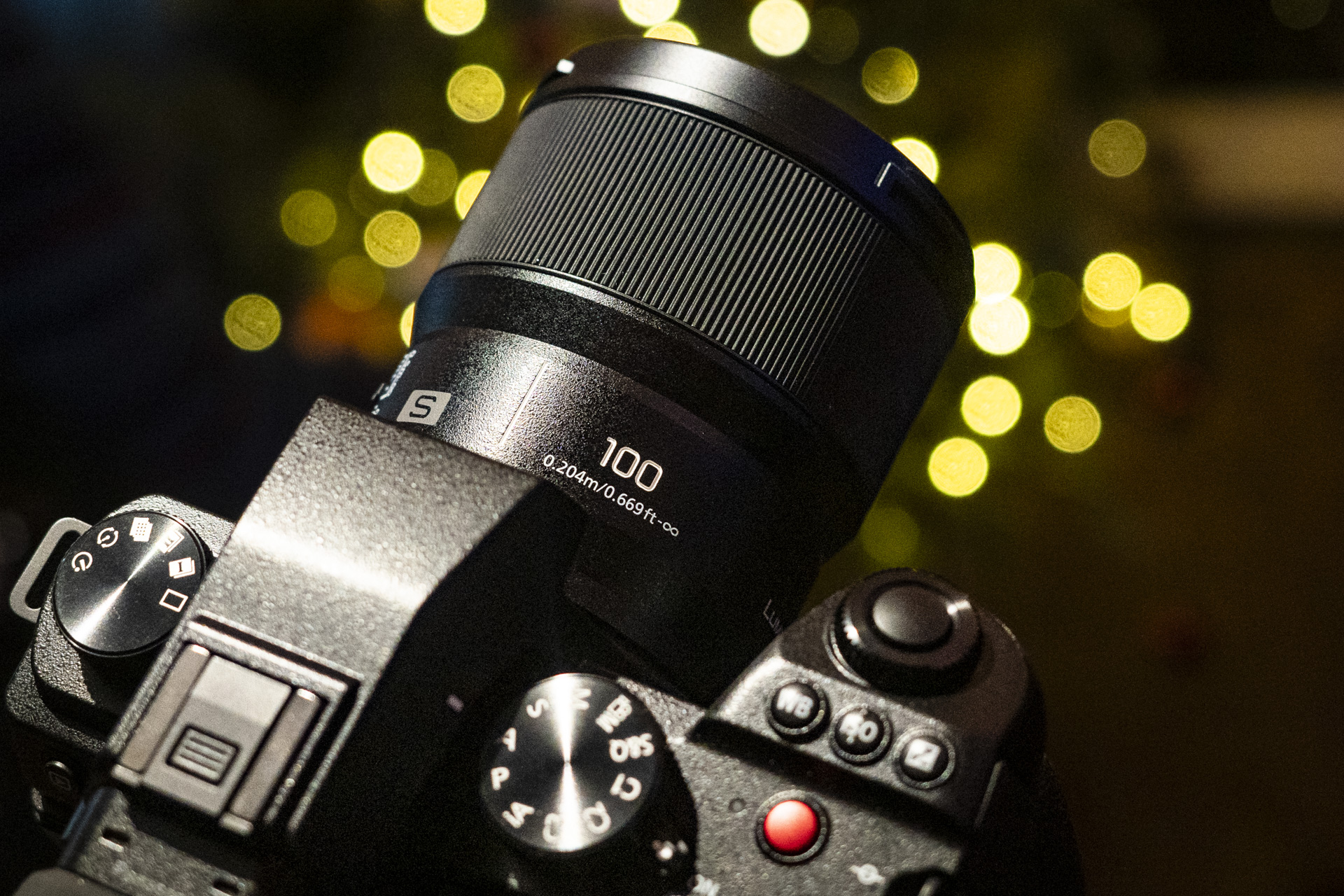 Panasonic Lumix S 100mm F2.8 Macro lens attached to a Lumix S5 II with Christmas lights behind