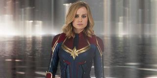 Carol Danvers (Brie Larson) wears her suit and stands in front of a blurry background in 'Captain Marvel'