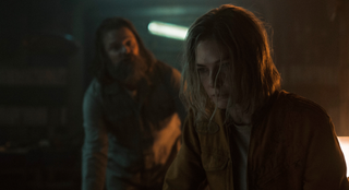 A disheveled woman and man in a dark bunker