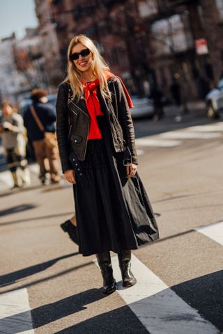 woman wearing leather jacket, red scarf, black skirt, and black boots