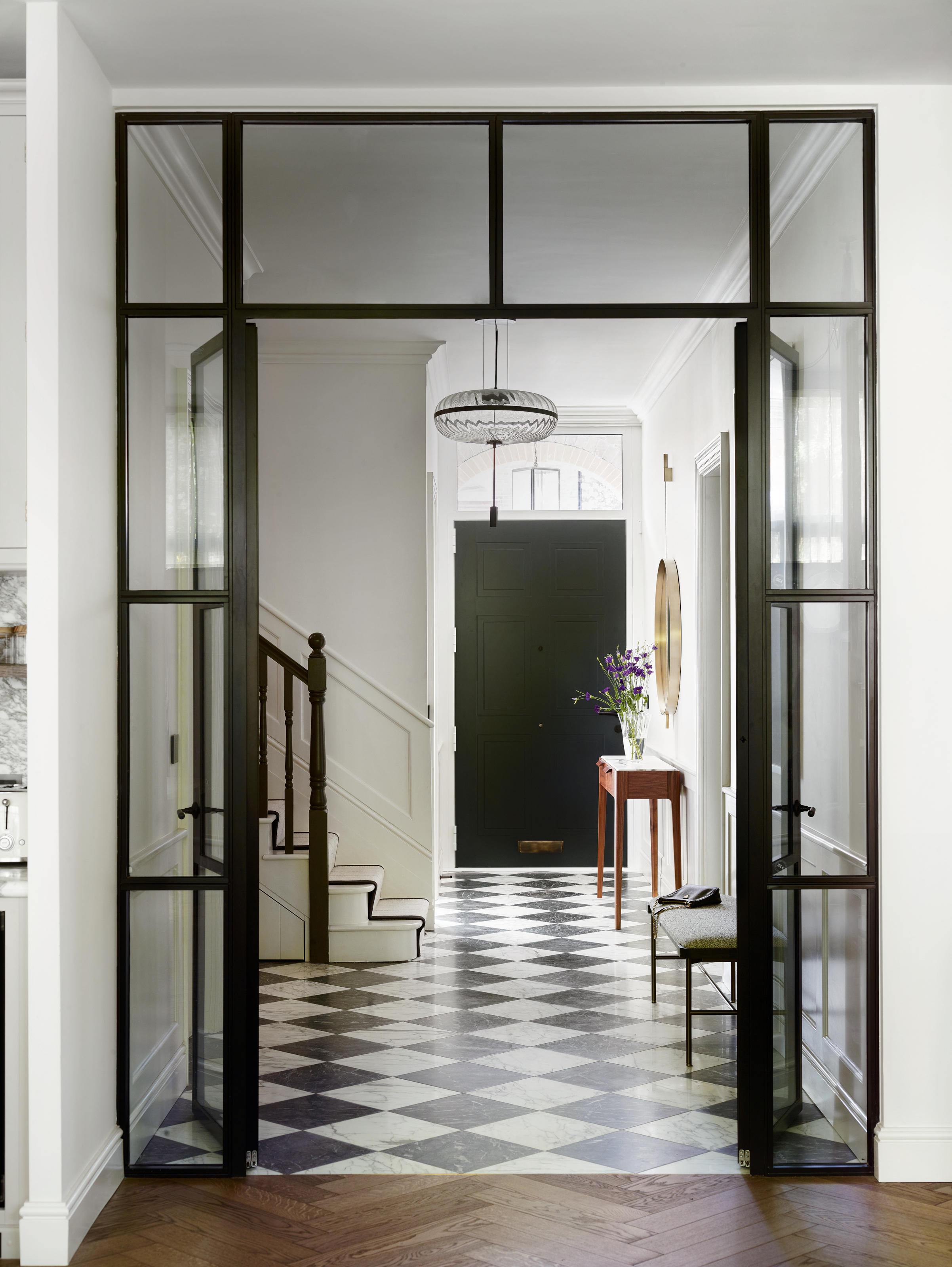 White hallway with black and white checkerboard floor, Crittall-style internal doors