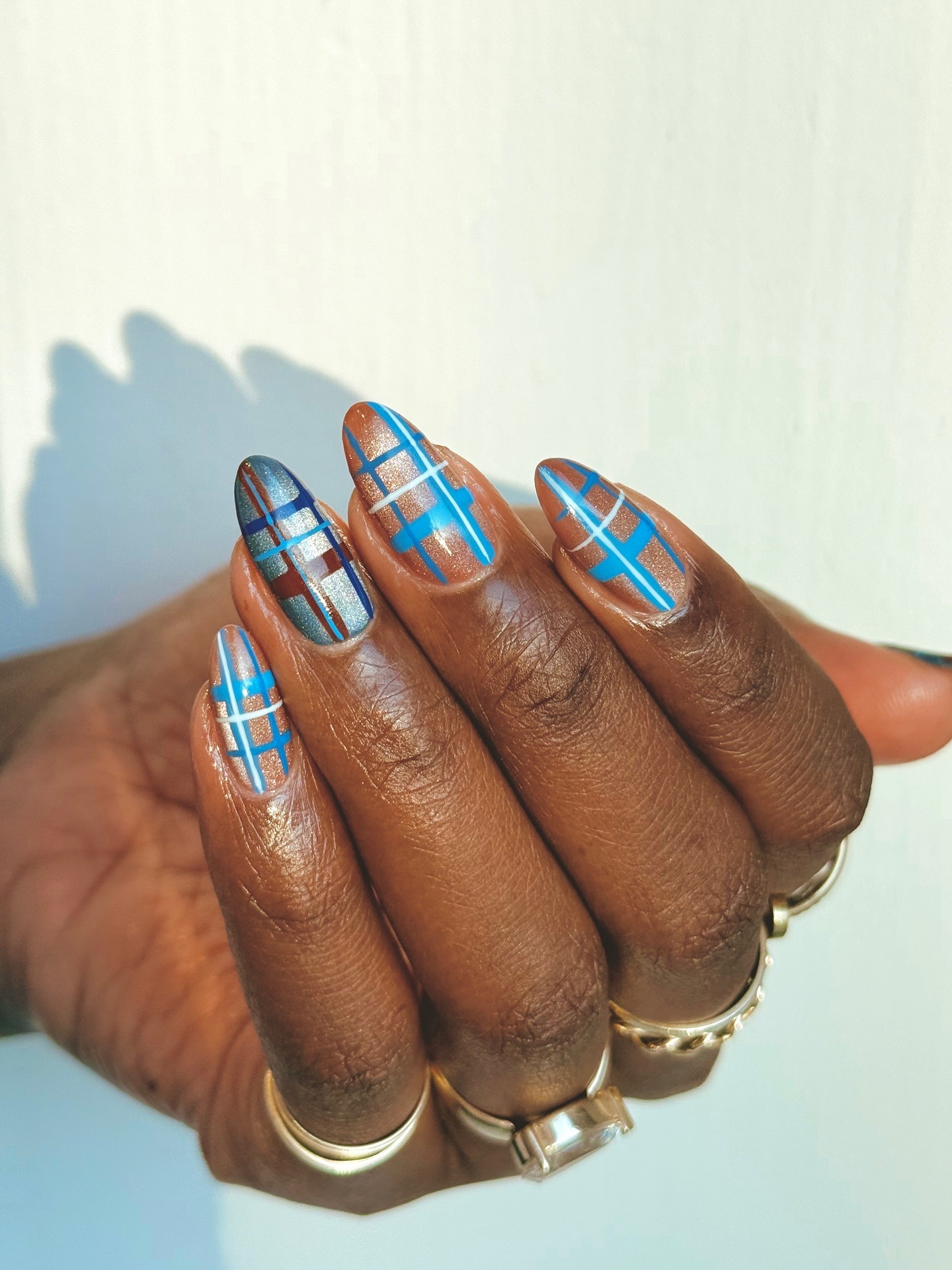 A blue and brown check nail design with a frosted, glittery finish