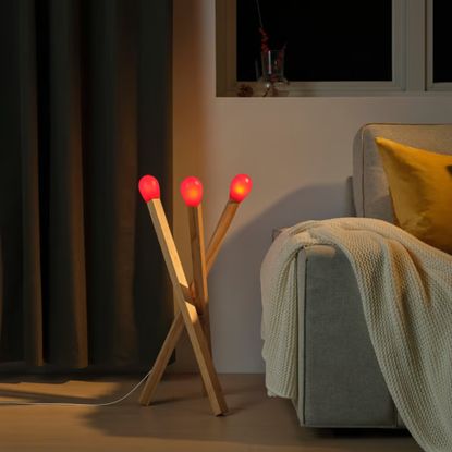 IKEA STRALA matchstick lamp on the floor next to a grey sofa