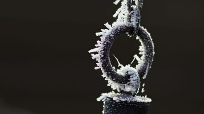 A frozen rain chain in a snowy environment