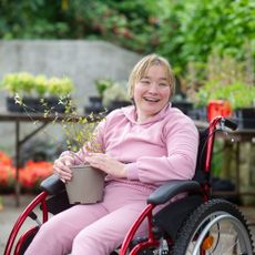 woman in wheelchair in garden holding plant
