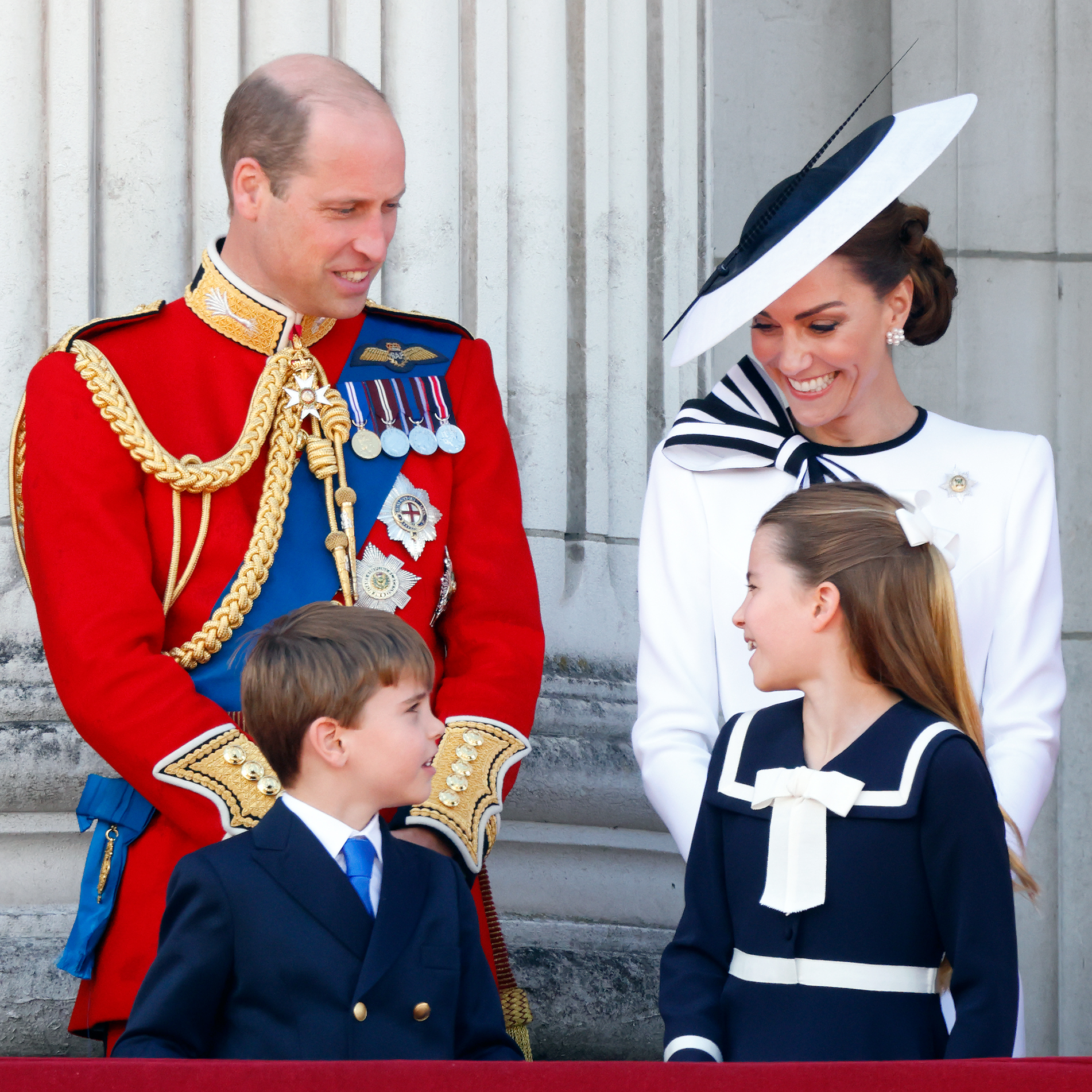 Princess Charlotte wearing a sailor dress smiling at Princess Kate, Prince William and Prince Louis at Trooping the Colour 2024