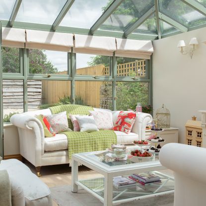 A conservatory with a living room set up with matching white sofas and an armchair