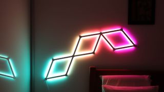 Bästa smarta belysning: Nanoleaf Lines sitter monterade på en vägg och lyser i olika färger.