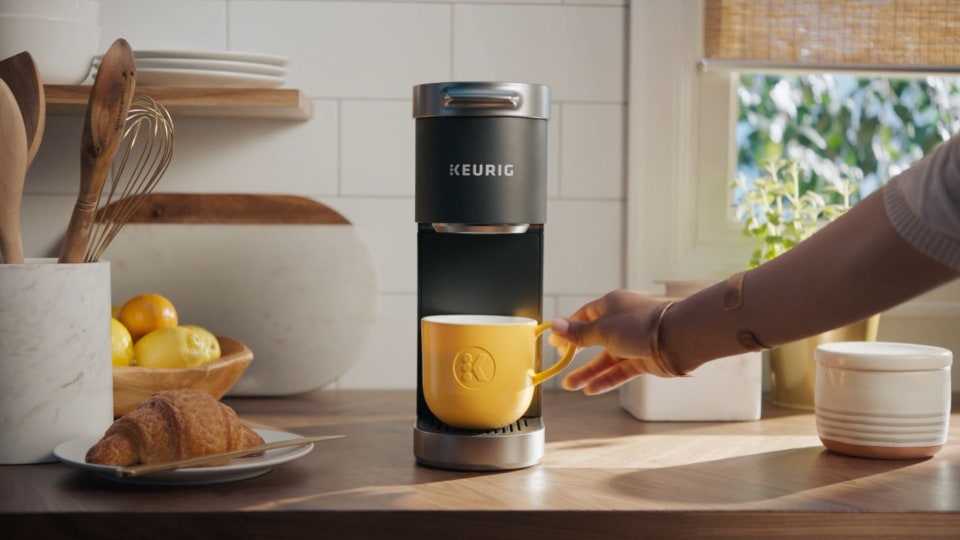 Keurig coffee maker with cup and hand