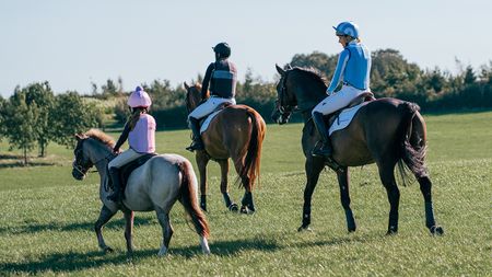 Three horse riders of different ages wearing body protectors