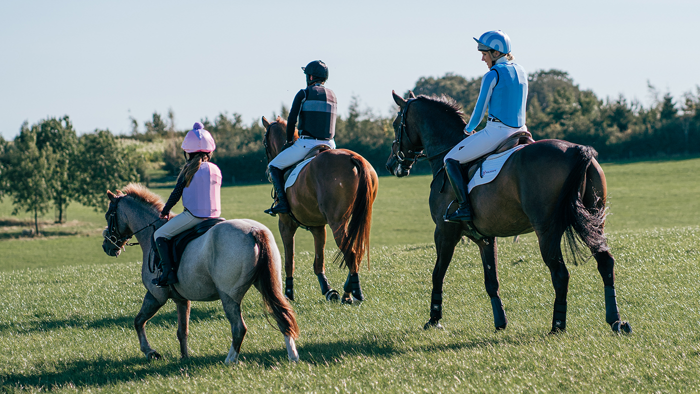 Three horse riders of different ages wearing body protectors