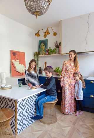 A family in a dark blue kitchen with large format patterned tiles and herringbone style floor tiles